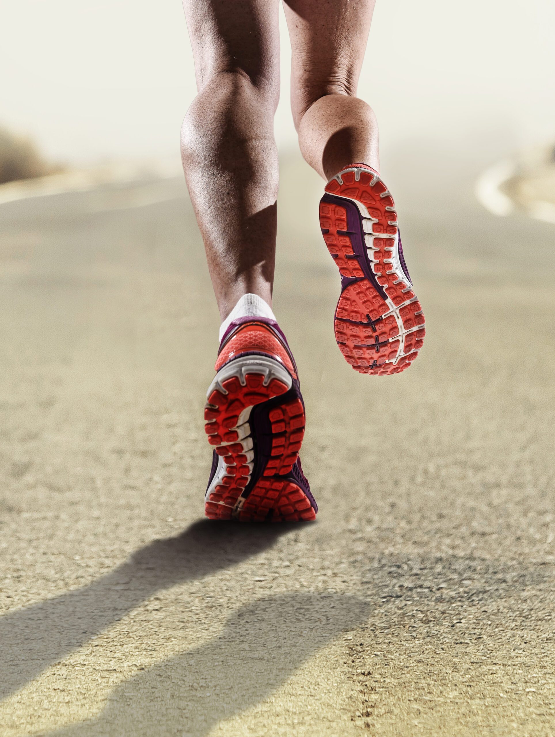 rear view close up strong athletic female legs and running shoes of sport woman jogging on asphalt road fitness healthy lifestyle high performance and endurance concept advertising style